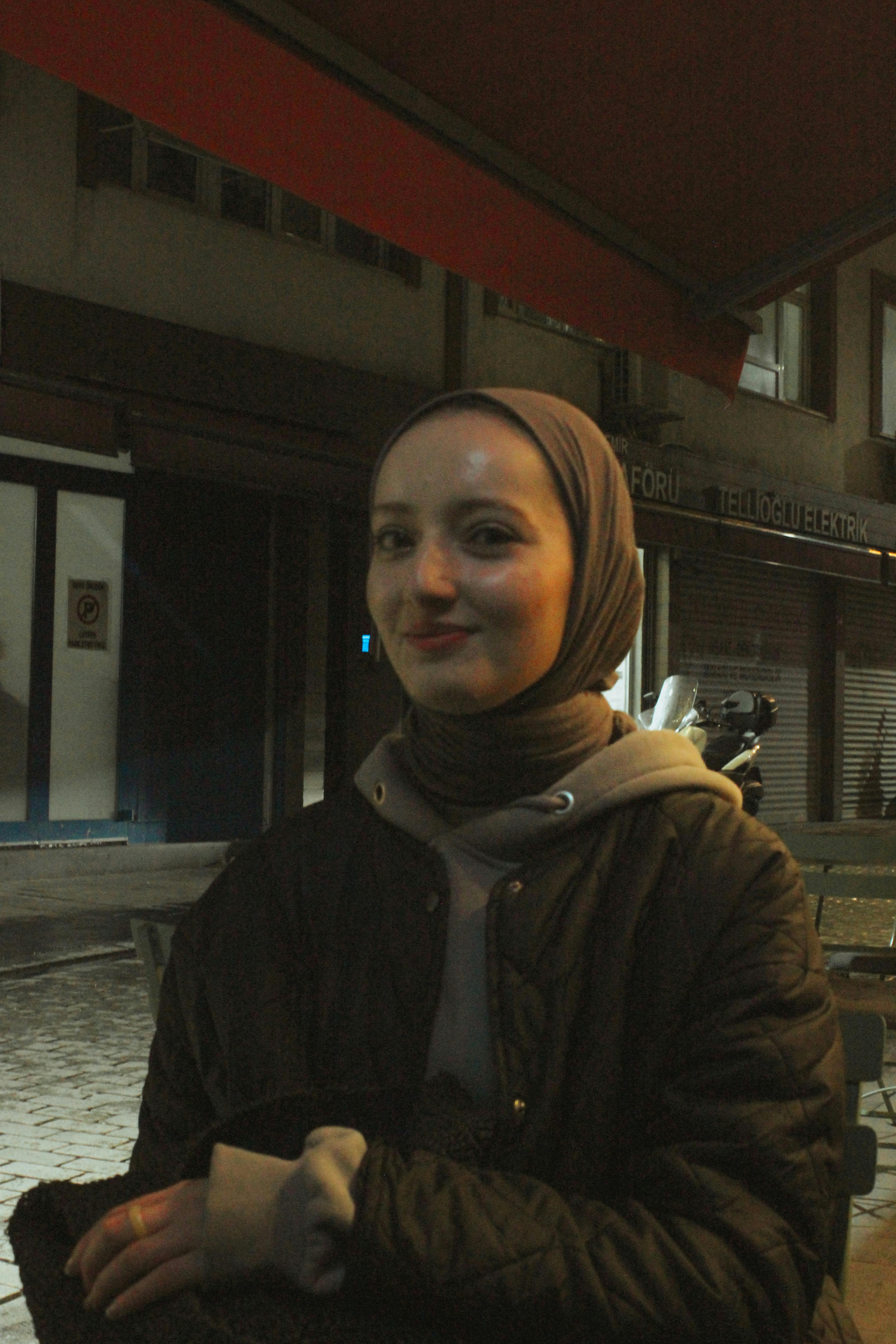Nighttime urban portrait of a smiling woman in Istanbul wearing hijab.