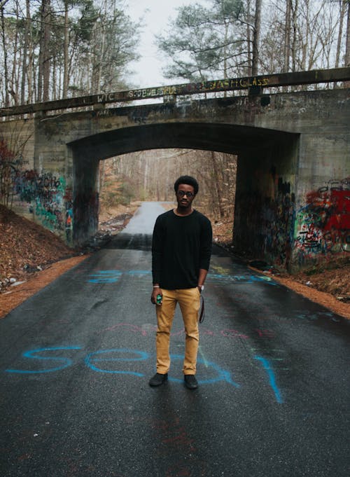 Man Standing Beside Gray Concrete Bridge