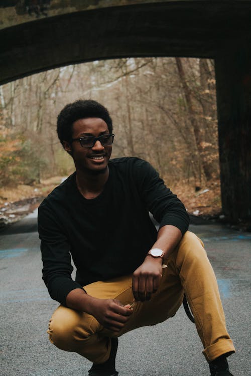 Smiling Man Sitting on Road Near Bridge