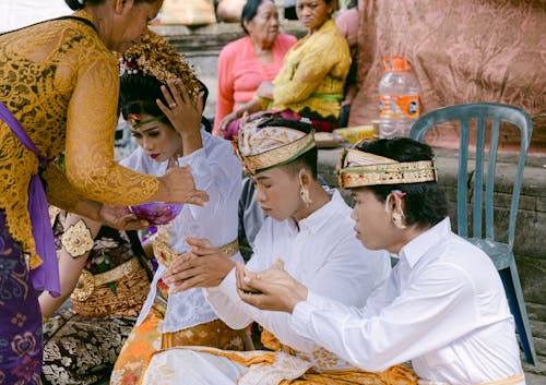 A woman in traditional clothing is giving a man a piece of food