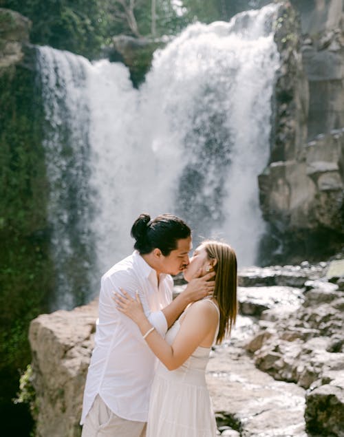 A couple kissing in front of a waterfall