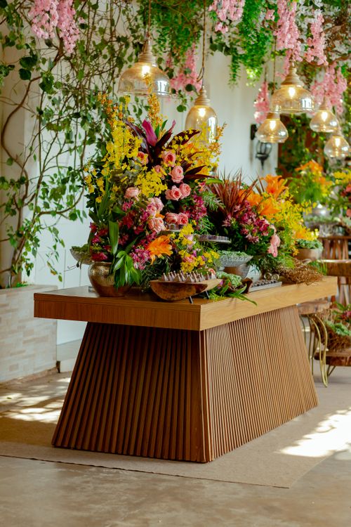 Free Luxurious indoor floral arrangement with vibrant flowers and hanging lamps on a stylish wooden table. Stock Photo