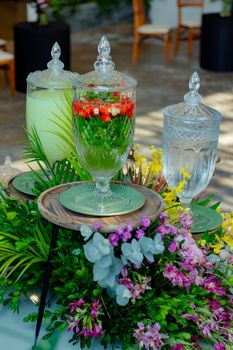 Elegant table setup with glass dispensers and vibrant floral centerpiece, ideal for events.