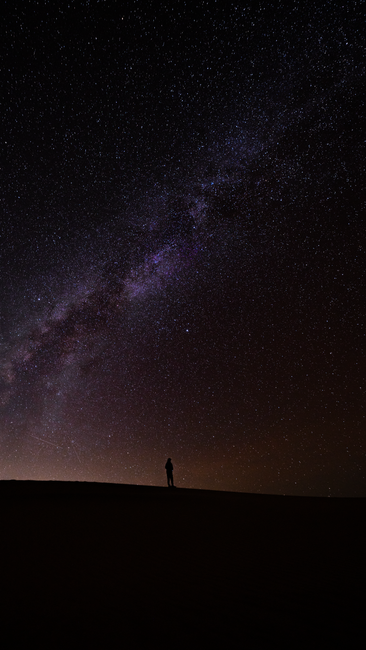 Fotomural Una silueta solitaria se encuentra bajo un vasto cielo nocturno estrellado que presenta la Vía Láctea en Death Valley Junction, CA.