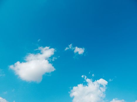 Serene blue sky with fluffy white cumulus clouds on a sunny day.