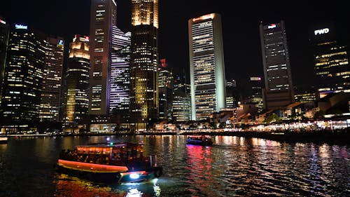 A boat is traveling through the water in front of a city