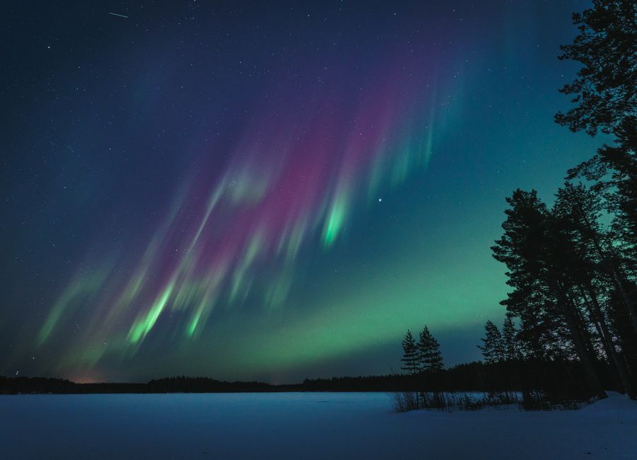 Northern lights illuminate the night sky over a serene lake in Oulu, Finland.