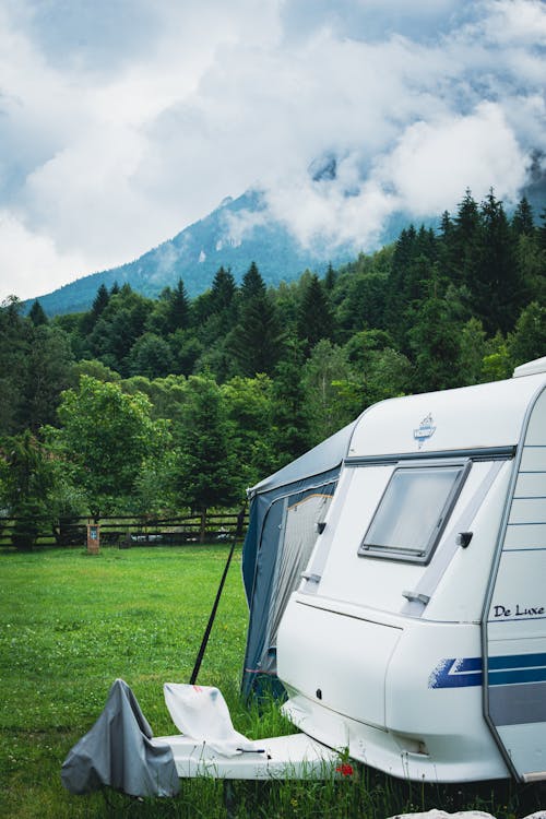 A camper trailer parked in a field with mountains in the background