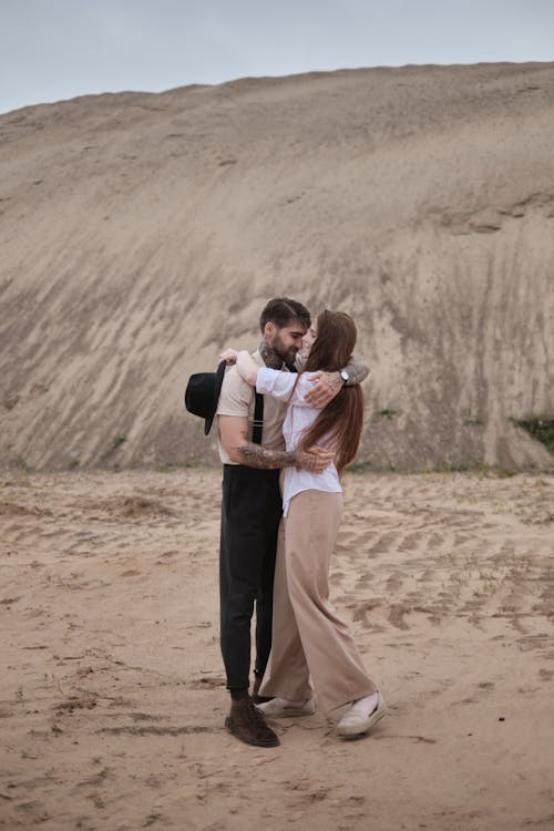 A couple hugging in front of a large sand dune