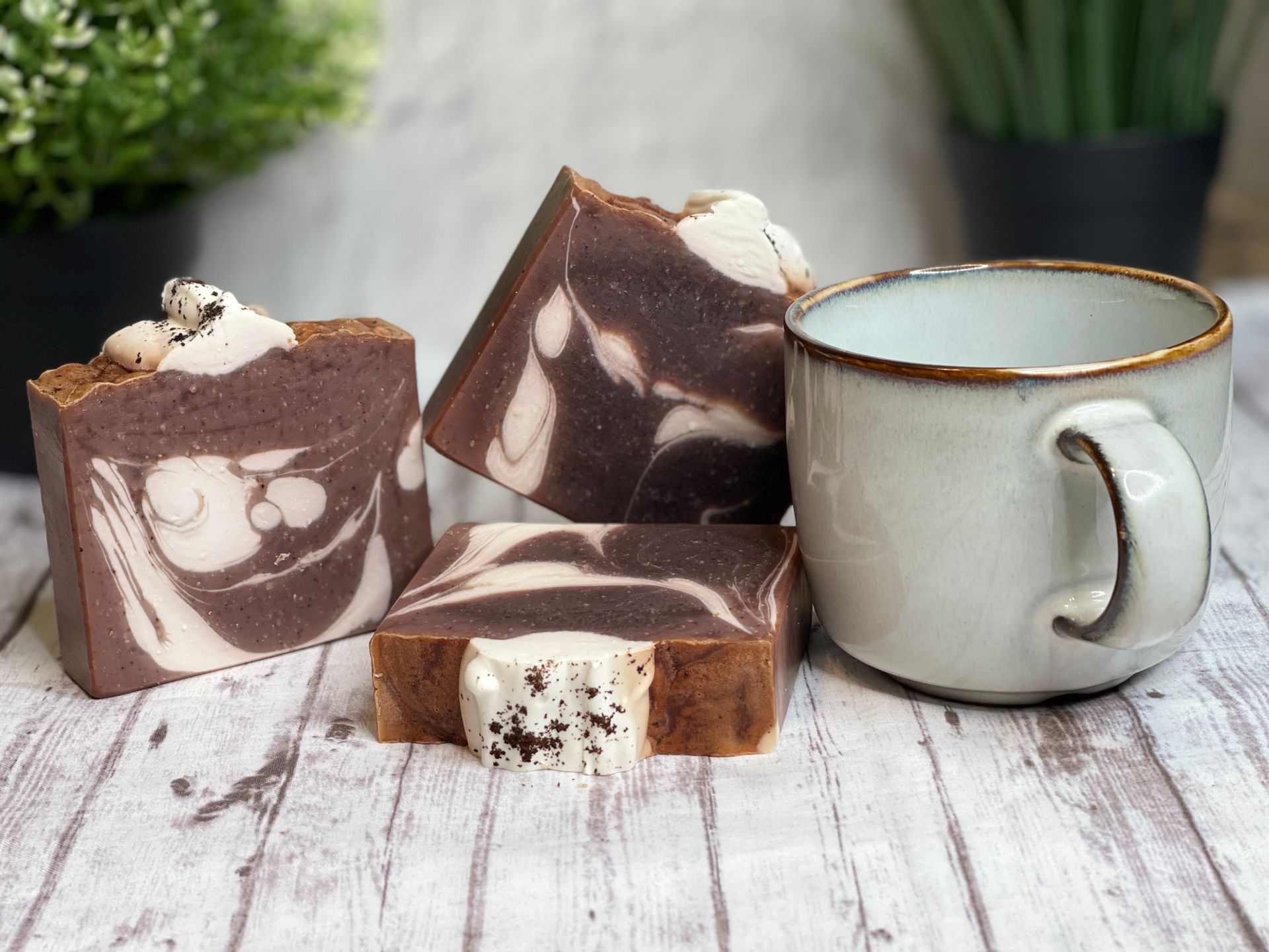 Artisan chocolate swirl soap bars with a rustic ceramic mug on wooden table.