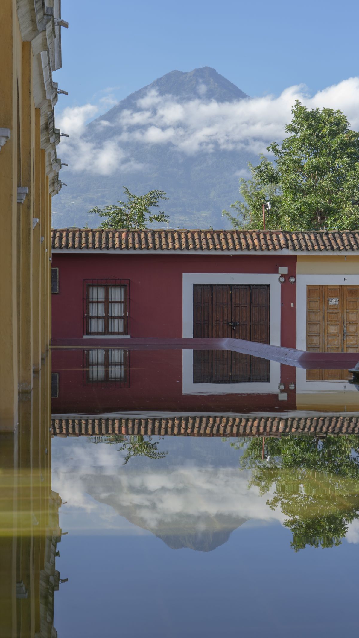 Volcán de Agua reflected in the water in front of a colonial house