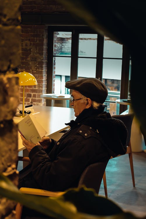 Darmowe zdjęcie z galerii z bluszcz czapka, czarna kurtka, czytanie