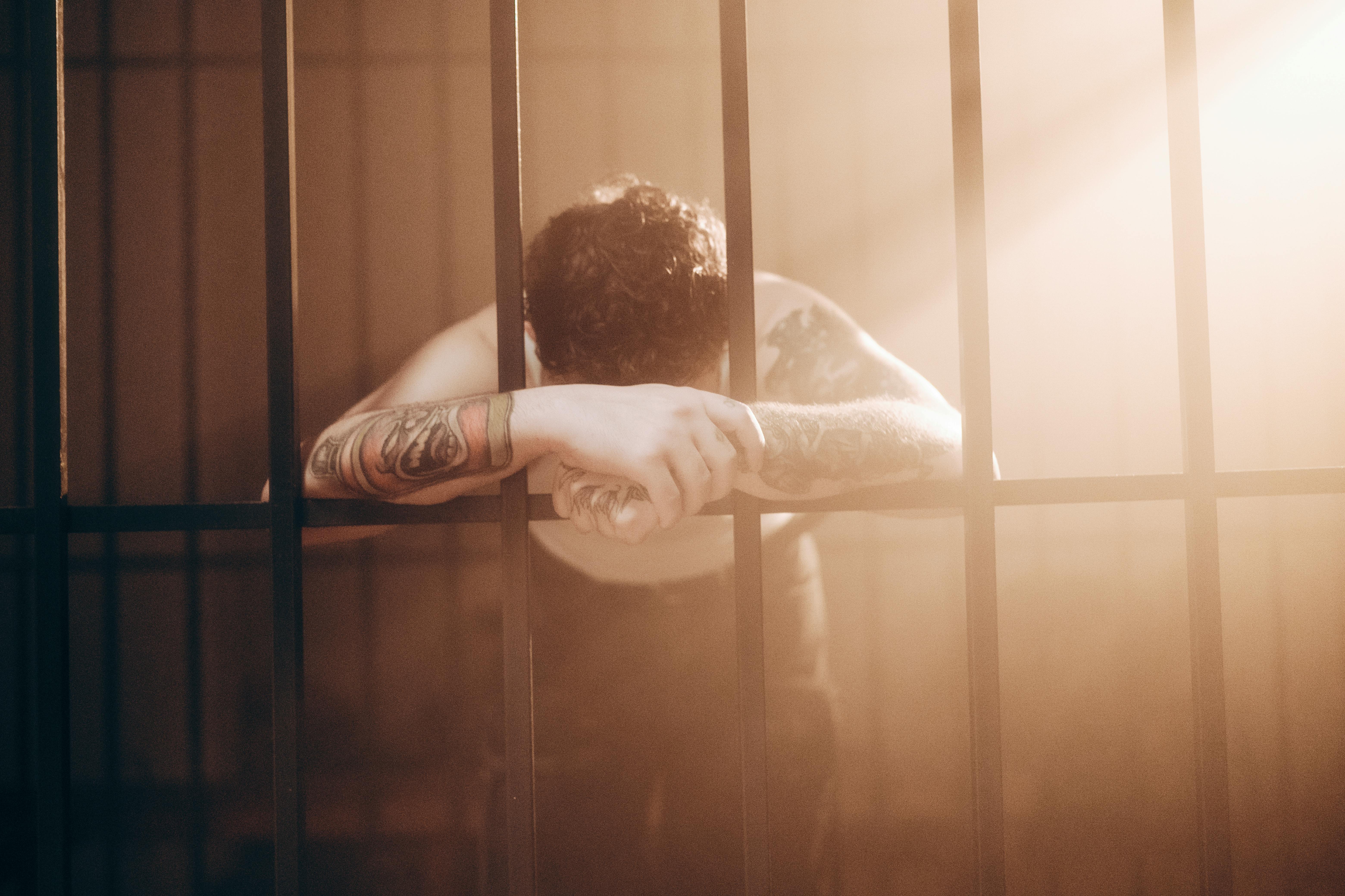 man leaning on bars in prison