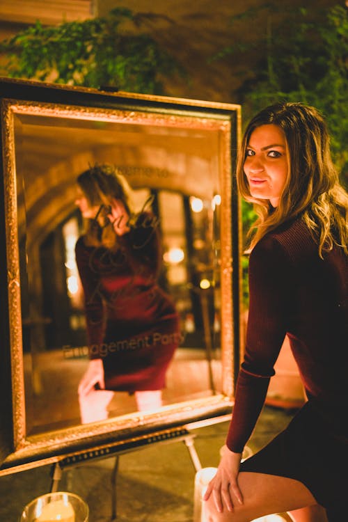 Young Woman Looking in Mirror at Her Engagement Party