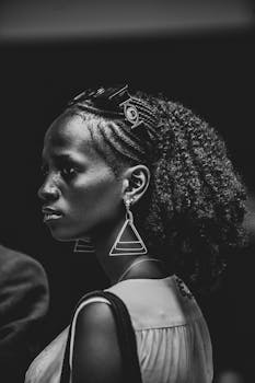 Striking black and white portrait showcasing a woman's unique style with triangular earrings and curly hair.