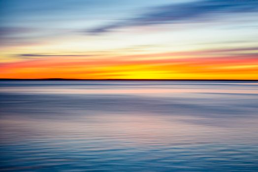Stunning sunset casting vivid colors over the calm ocean in Bay City, Oregon.