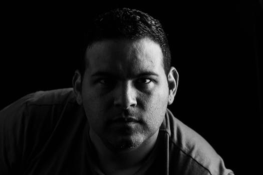 一幅引人注目的黑白肖像，描绘了一名男子在强光下摆出戏剧性的姿势