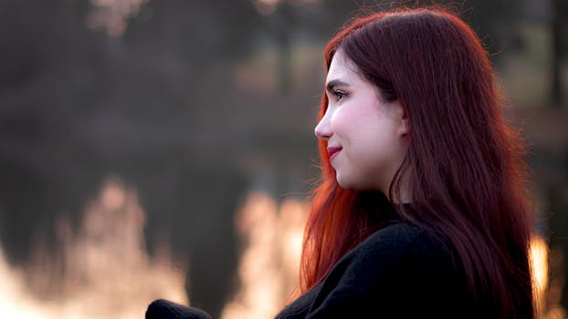 Profile portrait of a woman with red hair by a serene lake in Goslar, Germany.