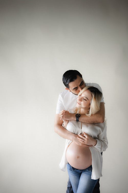 Man Standing and Kissing Pregnant Woman