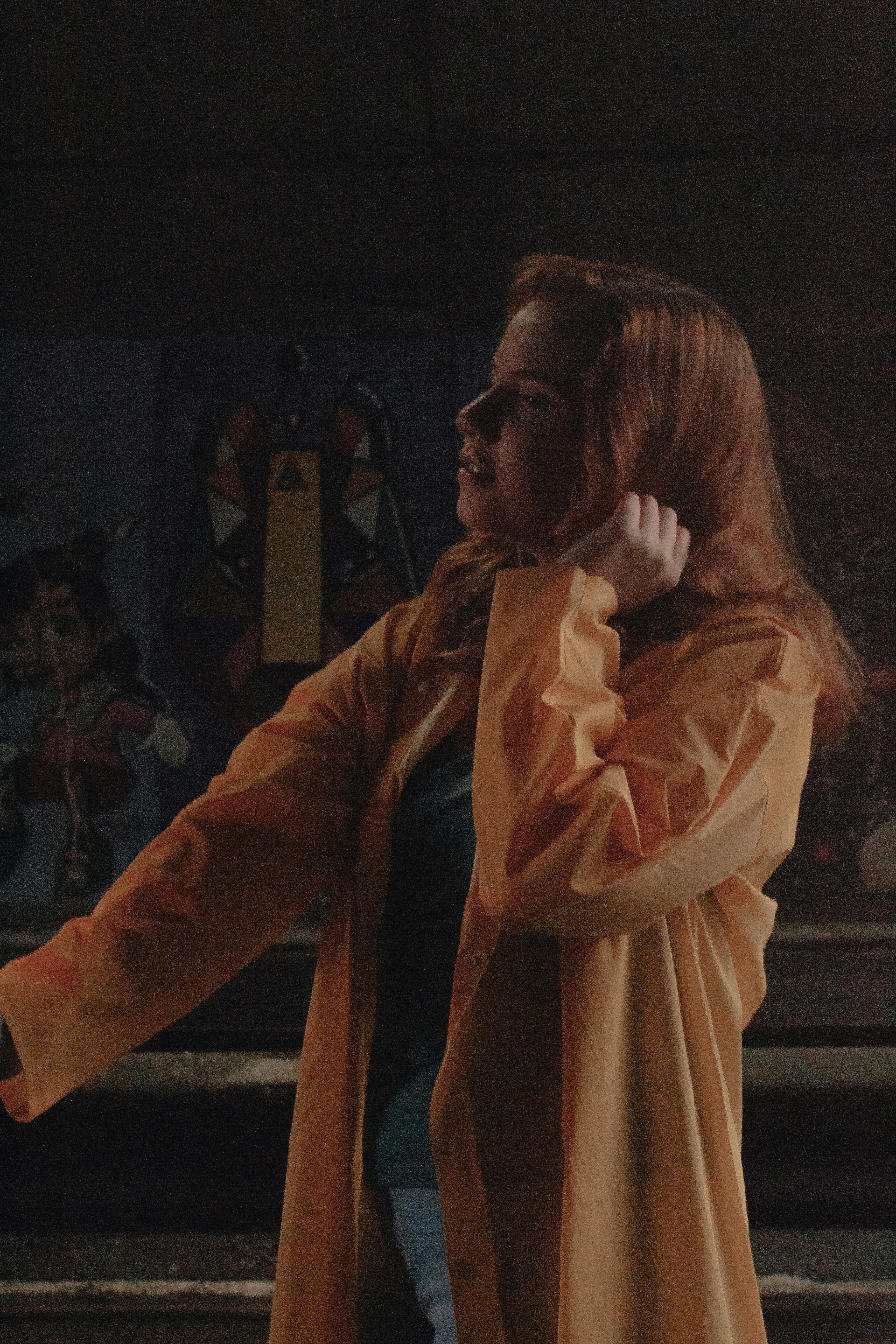 Artistic portrait of a woman wearing a yellow coat in an urban graffiti setting.