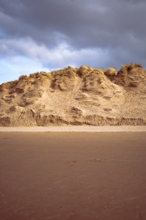 A sandy beach with a large sand dune