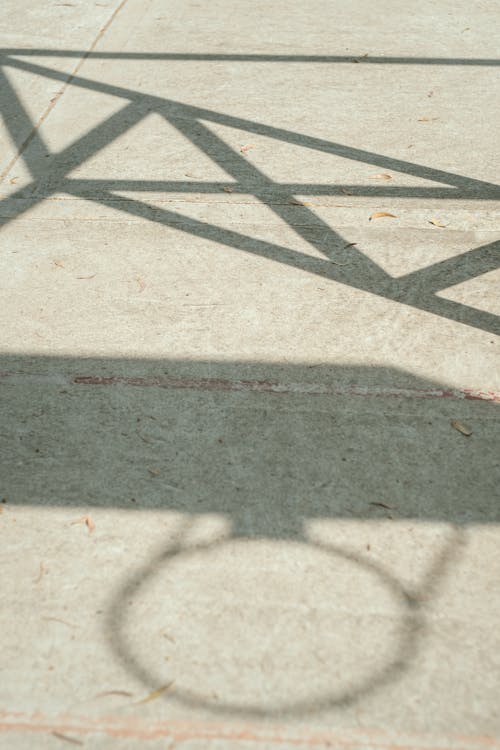 A shadow of a basketball hoop on a concrete floor