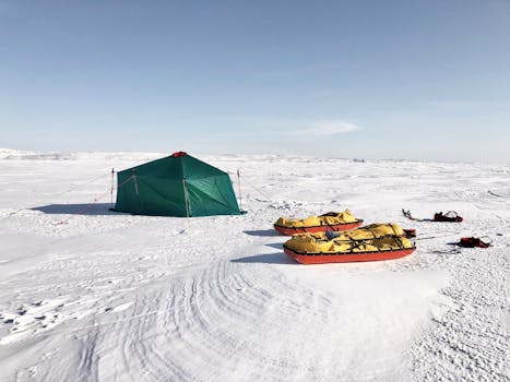 A vibrant green tent with sleds in a vast snowy landscape, ideal for winter camping adventures.