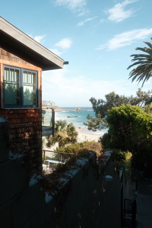 Free Serene coastal view featuring palm trees, beachfront, and a coastal home in tropical setting. Stock Photo