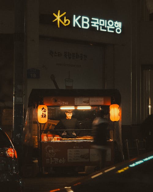 A street food stand at night with a sign that says kbb