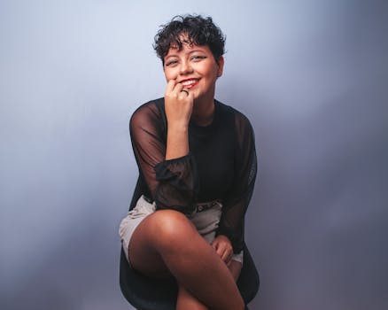 Portrait of a smiling woman with red lips and short hair in a studio setting.