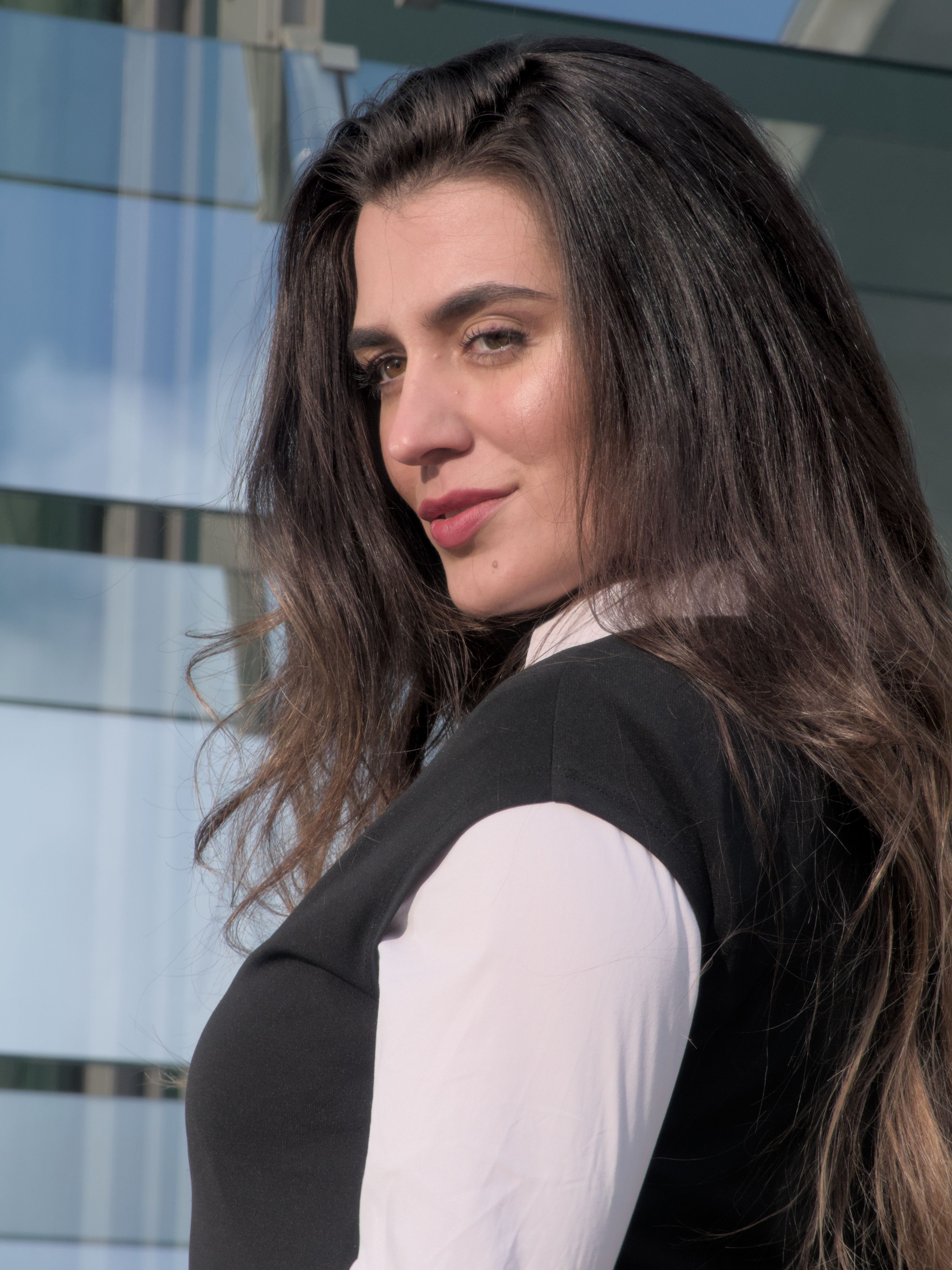 Portrait of a fashionable woman with long hair posing confidently outdoors, exuding elegance and style.