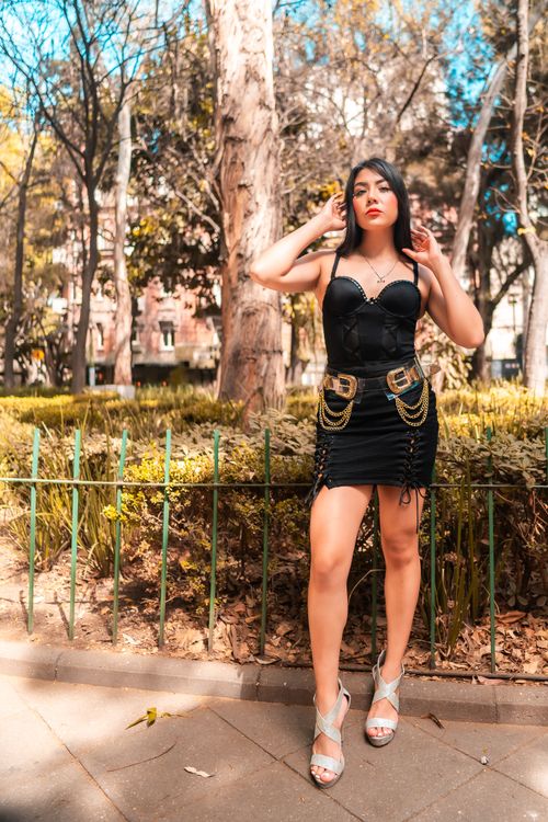 Free Fashionable woman in a black dress posing in a sunlit park in Mexico City. Stock Photo