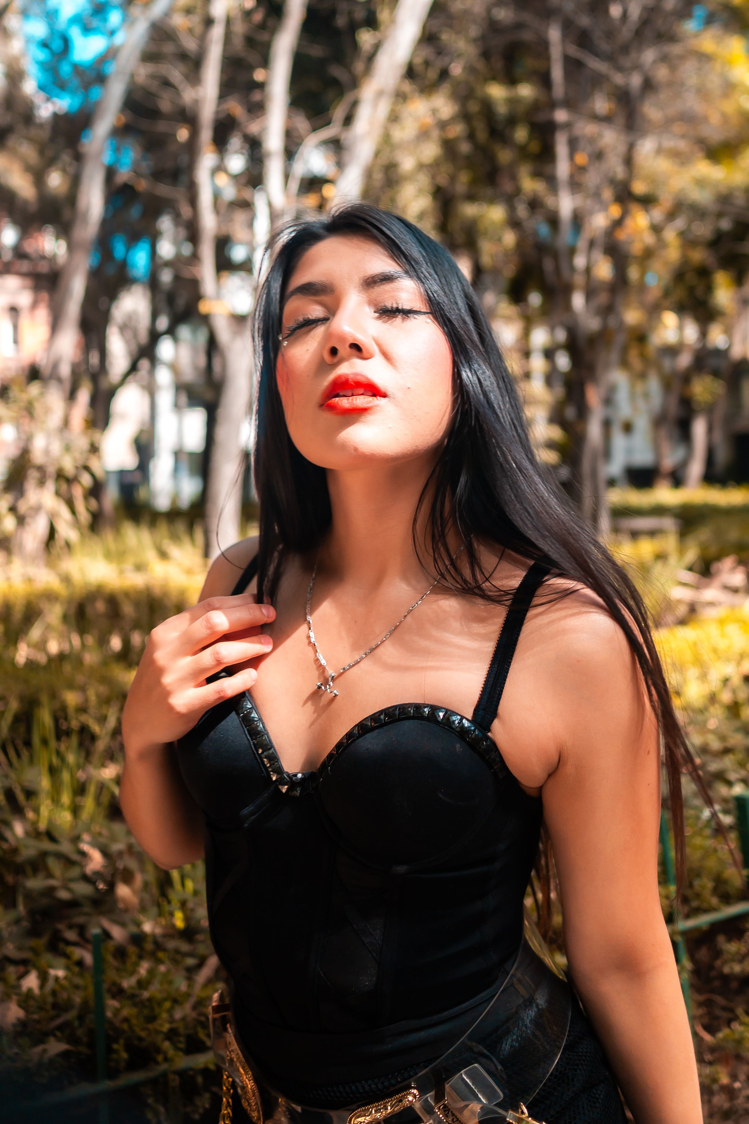 Chic woman in a black outfit posing confidently in Mexico City's vibrant green park setting.