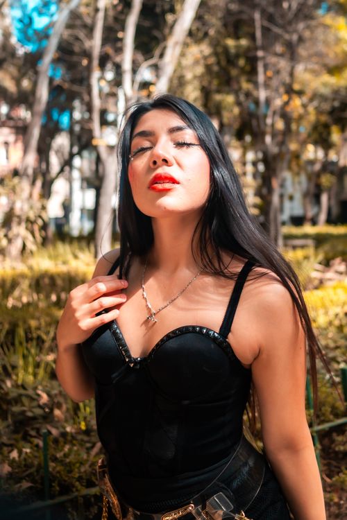 Free Chic woman in a black outfit posing confidently in Mexico City's vibrant green park setting. Stock Photo