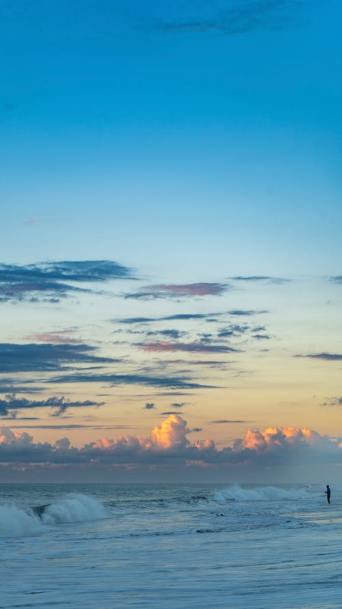 A person walking on the beach at sunset