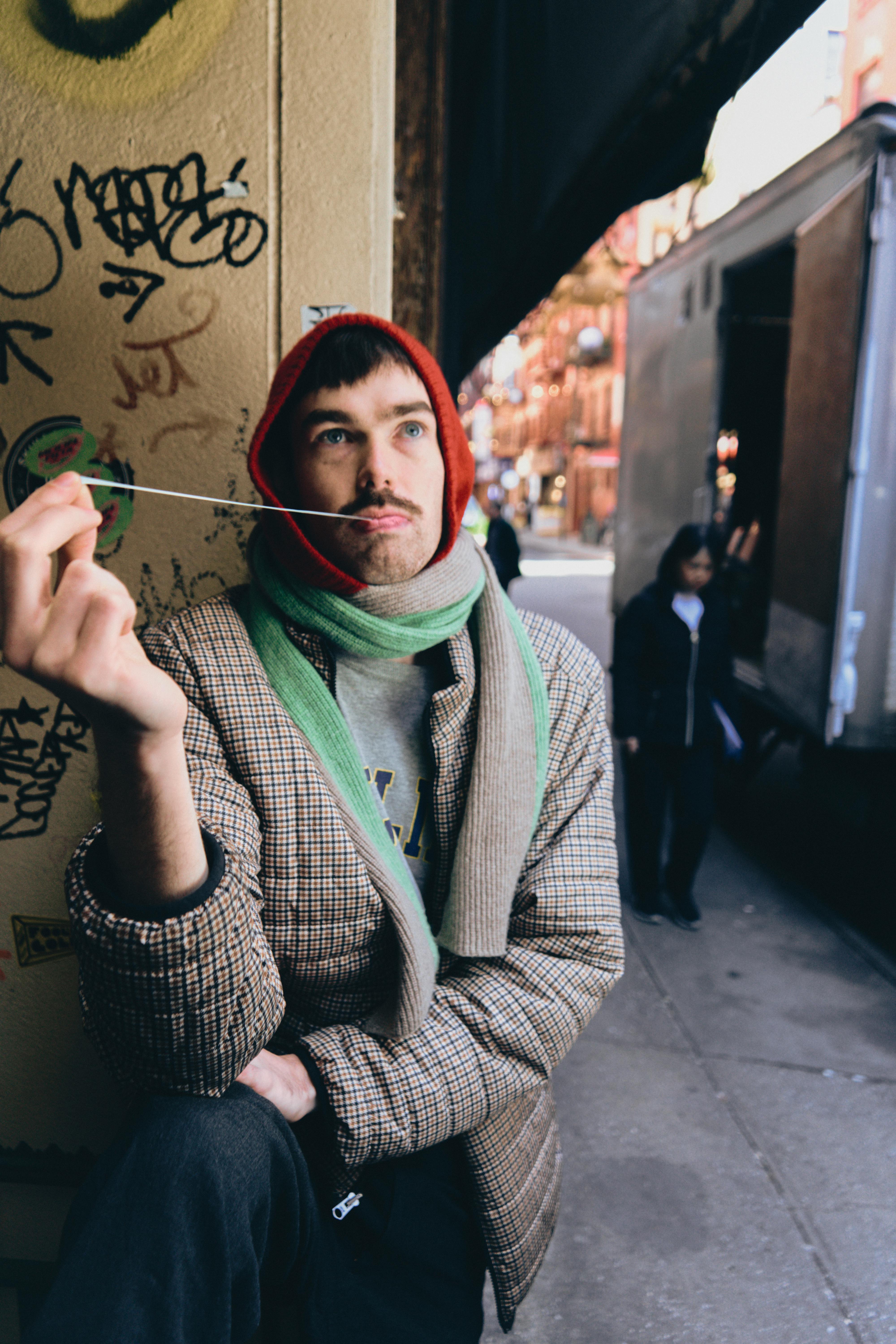 a man with a scarf and a hat is holding a piece of string