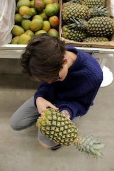 水果市场上，一个人在检查菠萝，周围摆满了新鲜的热带水果