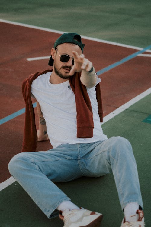 A man sitting on the ground with his hand up