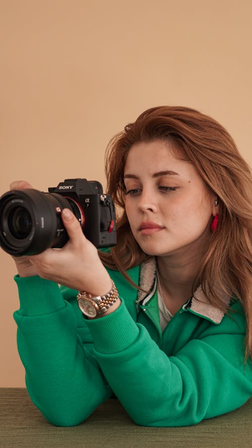 A woman in green sweater holding a camera