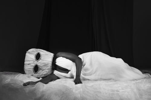Woman in Mask and Dress Lying Down on Bed