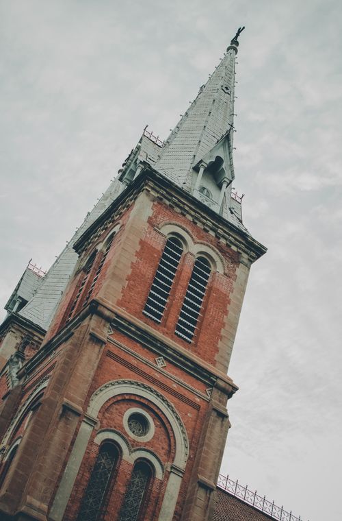 Free Low angle view of a gothic-style cathedral tower with red brick and stone detailing. Stock Photo