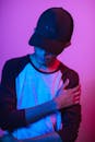 一位戴着紫色和蓝色灯光帽子的年轻人，其风格化肖像显得喜怒无常