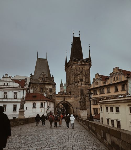 Free Gothic towers of Charles Bridge in Prague, with pedestrians exploring the historic architecture. Stock Photo