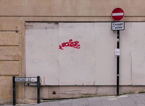 Street view featuring a no entry sign, graffiti, and signs on a city wall.