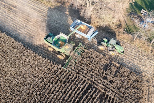 Aerial view of a tractor and a combine harvesting a field