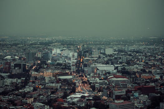 Aerial cityscape of Mexico City showcasing urban architecture and sprawling city lights after sunset.