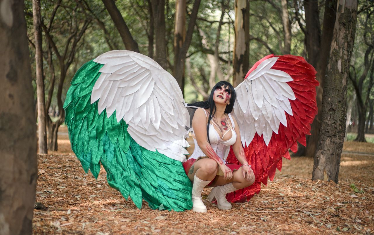 woman in elaborate wings and costume squatting in a vibrant forest set