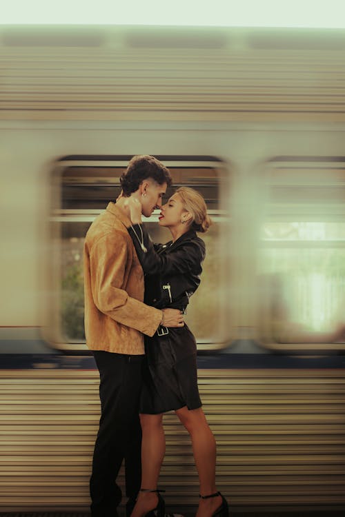 A couple kissing in front of a train