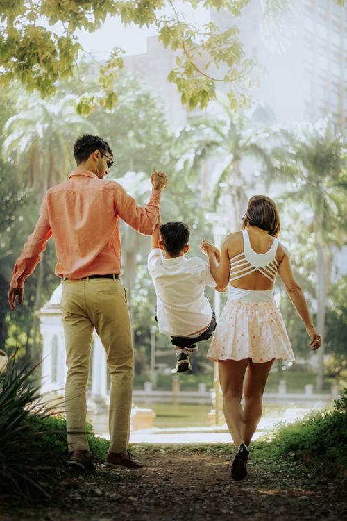 Free A family with a child enjoying a walk in a sunny park, creating joyful moments together. Stock Photo