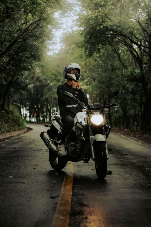 Free A biker on a motorcycle taking a break on a scenic forest road. Stock Photo